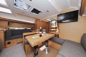 A compact RV interior with a dining area, seating, a flat-screen TV, and a kitchenette. - Sun-Kissed Sailing Adventure in Zadar, Croatia (Biograd na moru)