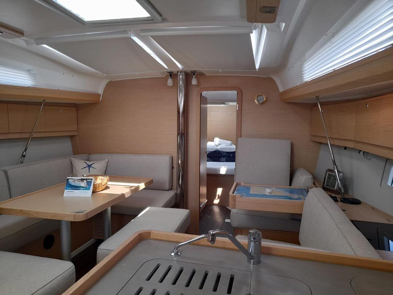 A compact RV interior with a kitchenette, seating area, and a small sleeping berth.