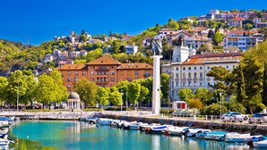 A marina with boats, a statue, and buildings with red roofs.