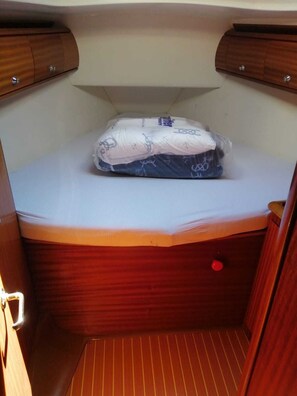 A compact, enclosed sleeping area with a bed, a small storage cabinet, and a red button. - Sun-Kissed Sailing Adventure in Northern Croatia (Rijeka)