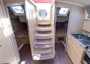 A compact RV interior with a kitchenette, a dining area with a table and chairs, and a small window. - Sun-Kissed Sailing Adventure in Split, Croatia (Split)