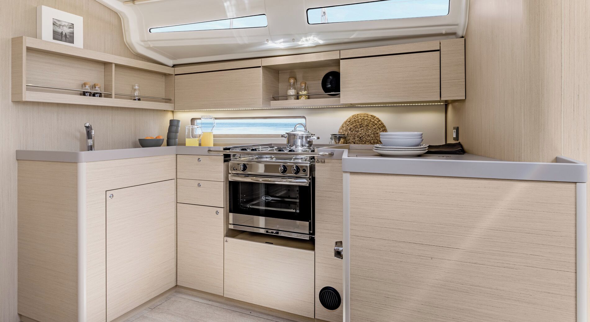 A compact kitchen with a built-in oven, wooden cabinets, and a window above the sink.