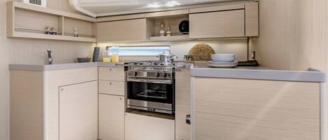 A compact kitchen with a built-in oven, wooden cabinets, and a window above the sink.