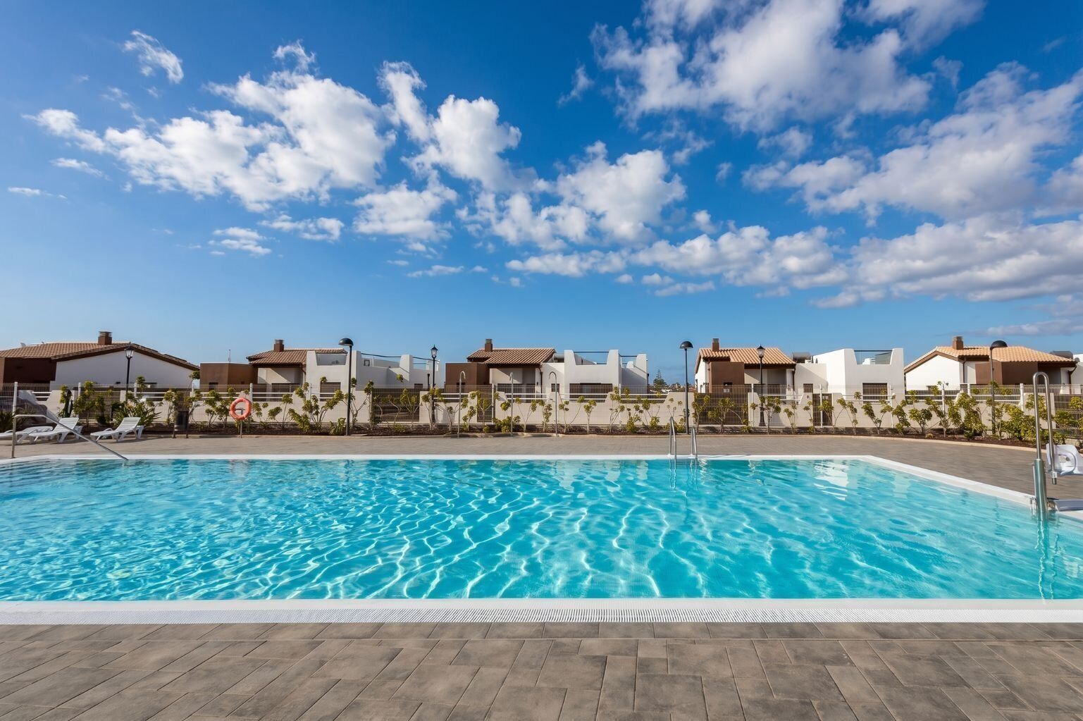 Une piscine à l’eau d’un bleu cristallin, entourée d’une terrasse carrelée.
