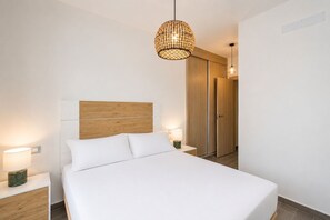 Ein modernes Schlafzimmer mit einem Holzkopfteil, einem großen Bett, Nachttischlampen und einer Pendelleuchte.