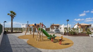 A playground with swings, a slide, and a seesaw. - GuestReady - Pueblo Majorero Sunny Stay and Pool (Antigua)