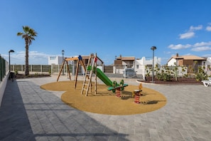 Ein Spielplatz mit Schaukeln, einer Rutsche und einem Wippen.