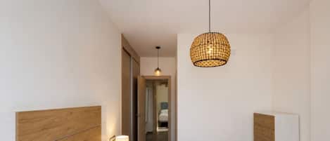 Habitación de hotel moderna con una cama grande, cabecera de madera, lámpara de noche y una lámpara colgante.