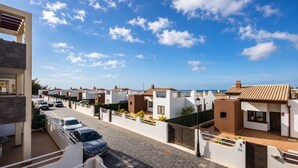 A residential area with modern houses, a paved street, and a clear blue sky. - GuestReady - Pueblo Majorero Sunny Stay and Pool (Antigua)