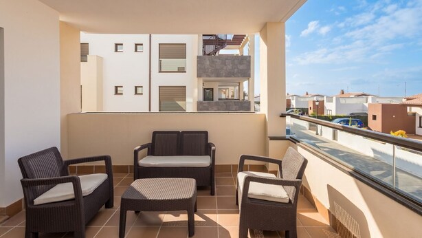 A balcony with wicker furniture, a view of neighboring buildings, and a clear sky. - GuestReady - Pueblo Majorero Sunny Stay and Pool (Antigua)