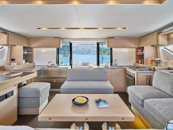 Een modern interieur met een centraal zithoek, keuken en grote ramen met uitzicht op het water.