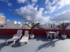 A rooftop terrace with lounge chairs, a table, and potted plants. - GuestReady - Rosamar 301 P (Las Palmas de Gran Canaria)