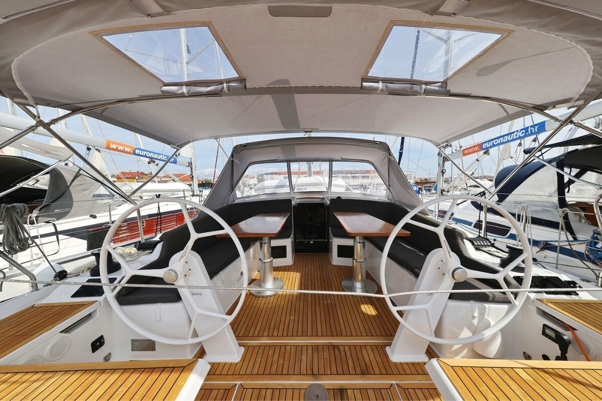 Ein Bootsdeck mit Steuer, zwei Tischen und einem Sonnensegel.