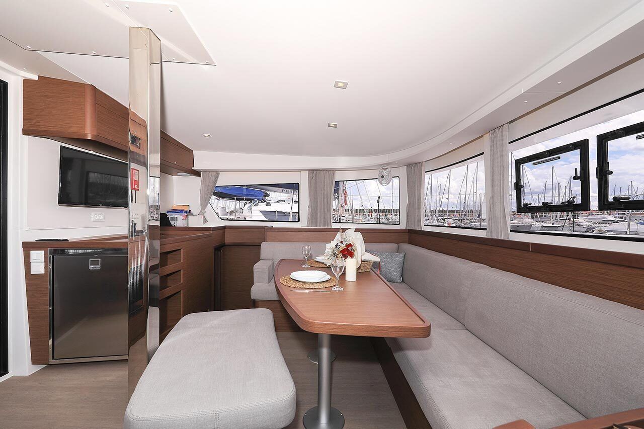 A modern interior with a dining area, a built-in TV, and windows with marina views.
