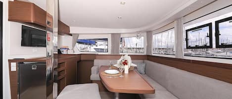 A modern interior with a dining area, a built-in TV, and windows with marina views.