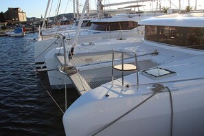 Un port de plaisance où sont amarrés de nombreux yachts, avec une zone de pont couverte comprenant un espace aménagé avec des sièges et une petite fenêtre.