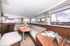 Et moderne interiør med spiseplads, siddepladser og store vinduer med udsigt over lystbådehavnen.