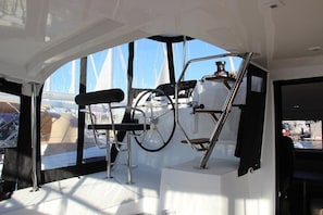 L'intérieur d'un bateau, avec un volant, un panneau de commande et un espace salon.