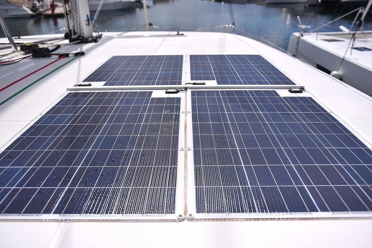 Ein Bootsdeck mit Solarmodulen und einem Jachthafen im Hintergrund.