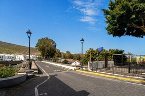 Eine gepflasterte Straße mit Bürgersteig, Straßenlaternen und blauem Himmel.