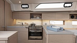 A compact kitchen with a gas stove, oven, and a sink. There are wooden cabinets and a countertop.