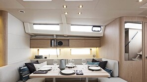 A compact dining area with a table set for two, overhead lighting, and a view of the upper deck.