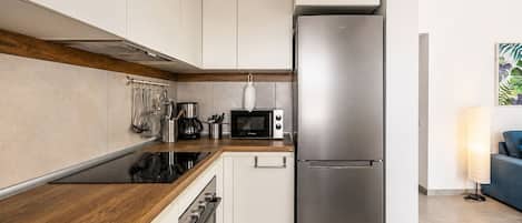 Una cocina moderna con un refrigerador de acero inoxidable, un microondas y una estufa.