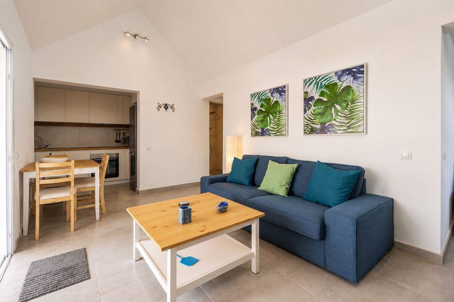 Una sala de estar moderna con un sofá, una mesa de centro de madera y un comedor con mesa y sillas.
