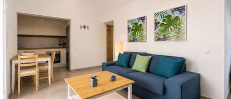 Una sala de estar moderna con un sofá, una mesa de centro de madera y un comedor con mesa y sillas.
