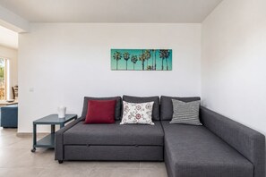 Una sala moderna con un sofá gris, una mesita y un cuadro en la pared.