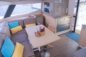 A compact galley with a dining table, cushioned seating, and a small kitchen area.