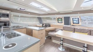 A modern kitchen with a microwave, stove, and sink. There is a dining area with a table and chairs, and a window with a view. - Caribbean Bliss: Sun-soaked Sailing Adventure from San Vicente y las Granadinas (Ribishi)