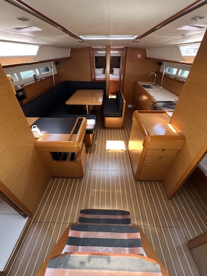 A compact interior with a dining area, seating, a small kitchenette, and a staircase. - Sun-Kissed Sailing Adventure in the Dodecanese Islands (Kos)
