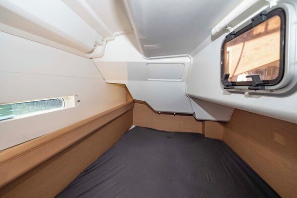 A compact cabin with a bed, a window, and a small storage compartment. - Sun-Kissed Sailing Adventure in Islas Baleares, Mallorca (Portocolom)