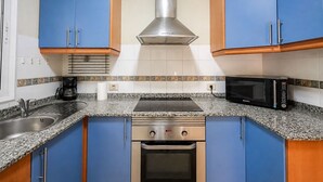 A kitchen with blue cabinets, a stainless steel range hood, a microwave, and a coffee maker. - GuestReady - Puerto Rico Bungalow with Pool (Puerto Rico)