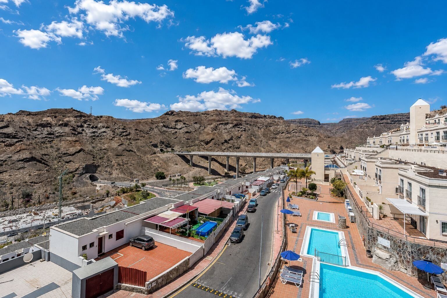 Un hotel junto a la costa con piscina, aparcamiento y vistas del paisaje rocoso circundante.