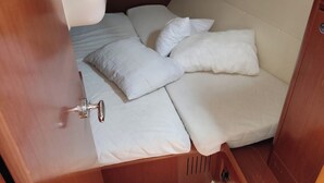 A compact, enclosed sleeping area with a bunk bed and a single bed, equipped with a small sink and a door. - Sun-Kissed Sailing Adventure in the Saronic Islands (Nea Peramos)