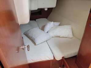 A compact, enclosed sleeping area with a bunk bed and a single bed, equipped with a small sink and a door.