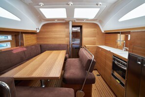 A compact galley with a wooden table and seating, a stove, and a small kitchen counter. - Sun-Kissed Sailing Adventure in Zadar, Croatia (Biograd na moru)
