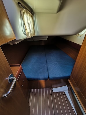 Un espacio interior reducido con una cama, un ventanal con cortinas y una puerta con manija.