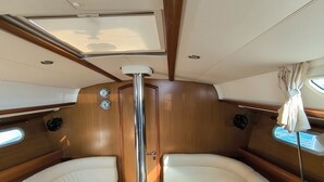 A boat interior with a central dining table, cushioned seating, and a window. - Sun-Kissed Sailing Adventure in Islas Sarónicas (Piraeus)