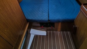 A compact interior with a bed, a window, and a wooden floor. - Sun-Kissed Sailing Adventure in Islas Sarónicas (Piraeus)