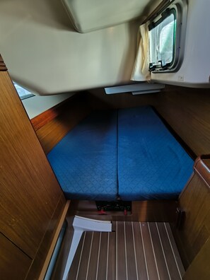 Un intérieur compact comprenant un lit, une fenêtre et un plancher en bois.