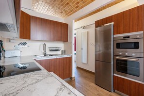Eine moderne Küche mit Holzausstattung, einem Edelstahlkühlschrank und einem Backofen.