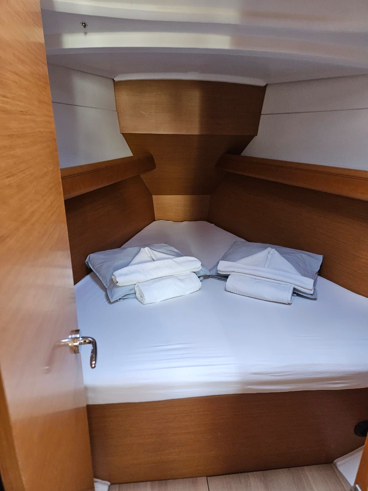 A compact, wooden interior with a small bed and neatly folded towels.