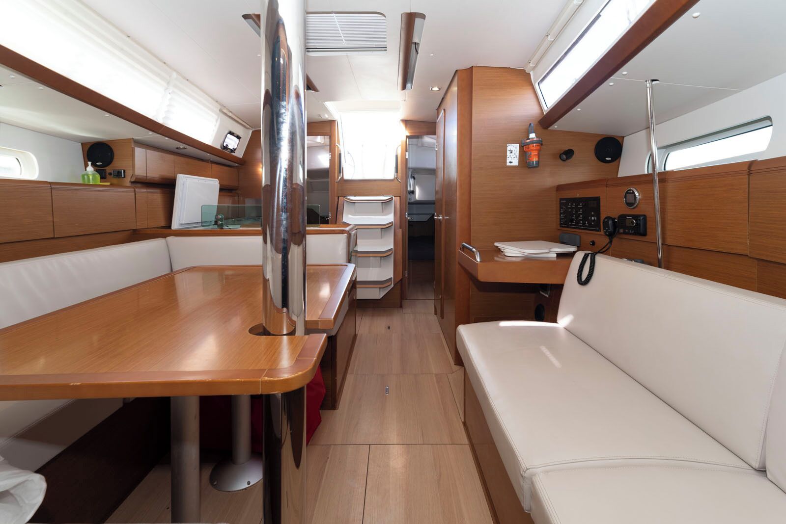 Un interior compacto con una mesa de madera, asientos blancos acolchados, un panel de control y una ventana.