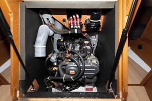 Ein kleiner Maschinenraum mit sichtbaren Schläuchen, einem Bedienfeld und einem schwarzen Motor.