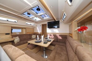 Ein modernes Wohnmobil-Interieur mit Essbereich, Sitzgelegenheiten, einem Flachbildfernseher und Dachfenstern.