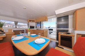 A compact kitchen with modern appliances, a dining area with blue placemats, and a view through the windows. - Sun-kissed Sailing Adventure in Split-Dalmatia, Croatia (Trogir)
