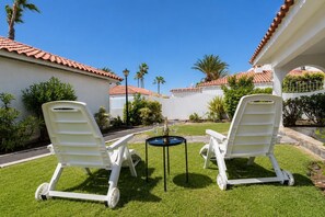 Terassi, jossa on kaksi valkoista aurinkotuolia, pieni pöytä ja samppanjapullo.